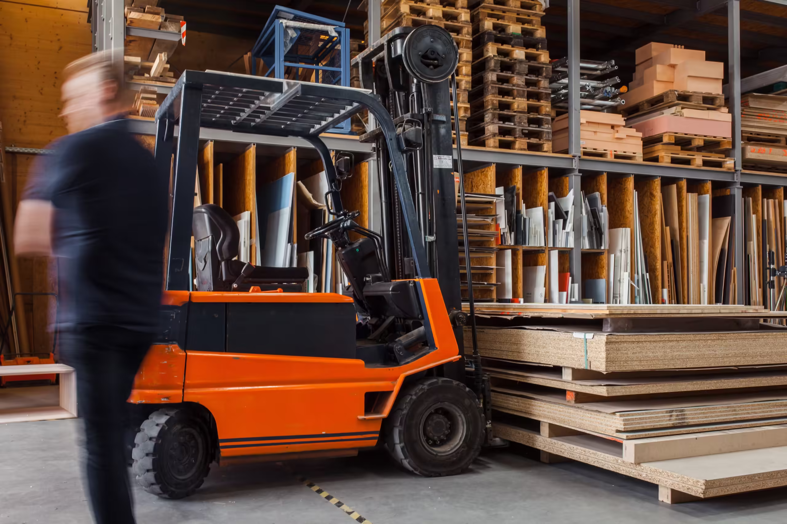 miljöbild på lager med fokus på en orange truck som flyttar skivor