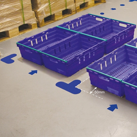blå golvmarkörer runt plastlådor i ett lager.